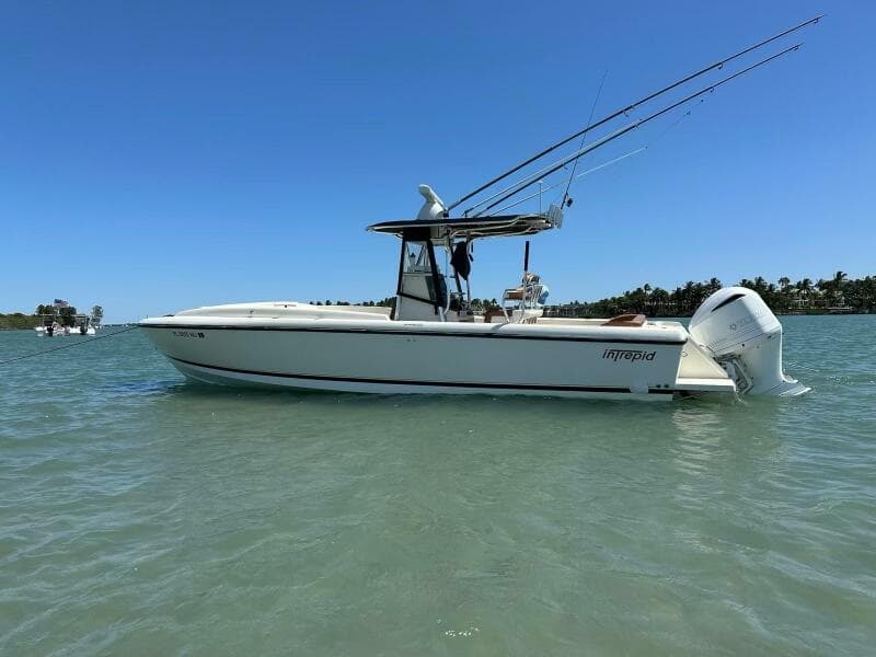 2004 Intrepid 32 Cuddy boat on water, clear sky, fishing rods visible.