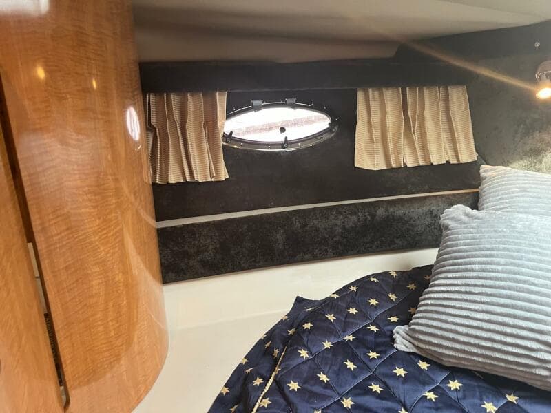 2003 Regal Commodore 3860 cabin interior with bed, porthole, and wooden cabinetry.