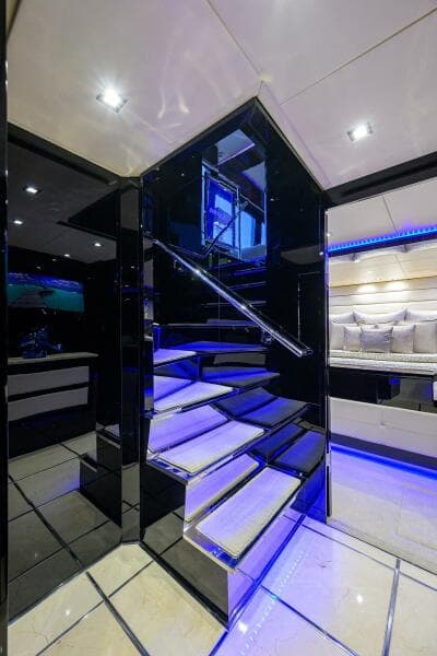 Luxurious interior of 1997 Broward 108 Raised Pilothouse yacht with modern staircase and blue LED lighting.