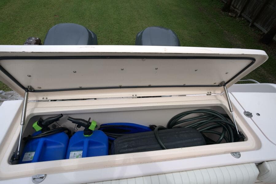 Open storage compartment on 2007 Grady-White Express 330 boat with blue containers and hose.