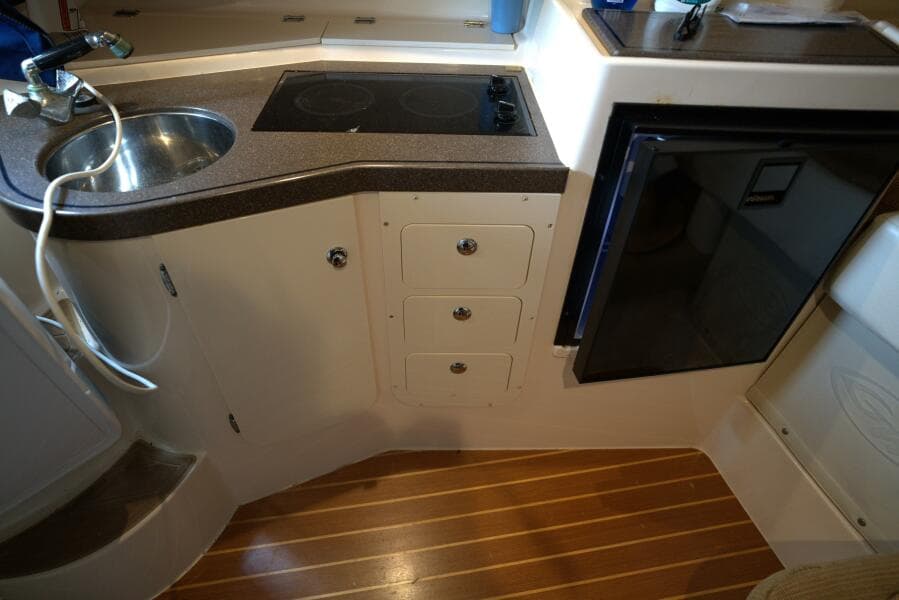 2007 Grady-White Express 330 boat kitchen with sink, stove, and mini fridge.