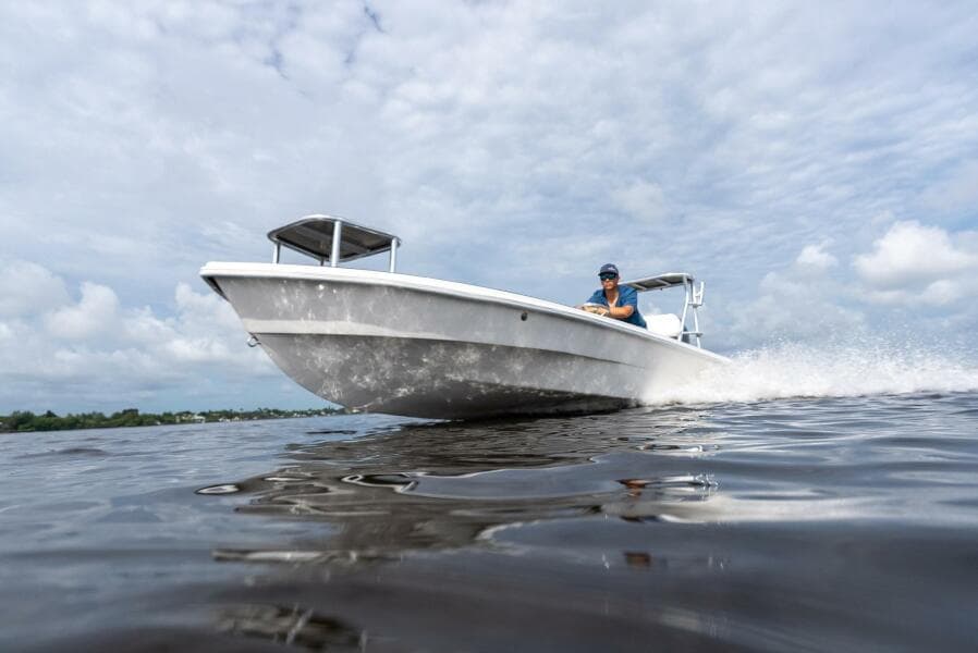 2025 BlueZones Boatworks 16' Flats boat cruising on open water under cloudy skies.