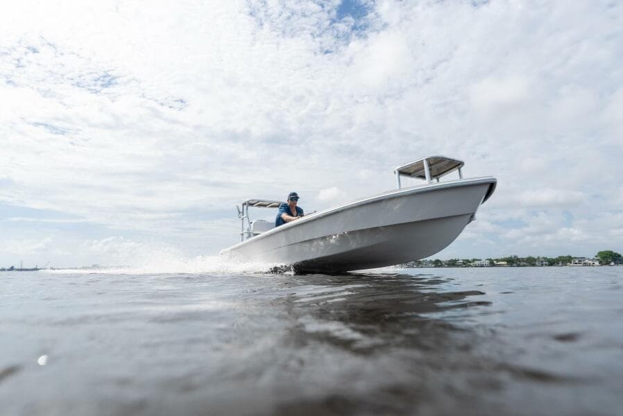 2025 BlueZones Boatworks 16' Flats cruising on open water under a cloudy sky.