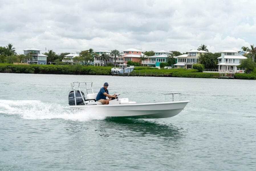 2025 BlueZones Boatworks 16' Flats cruising on water near coastal homes.