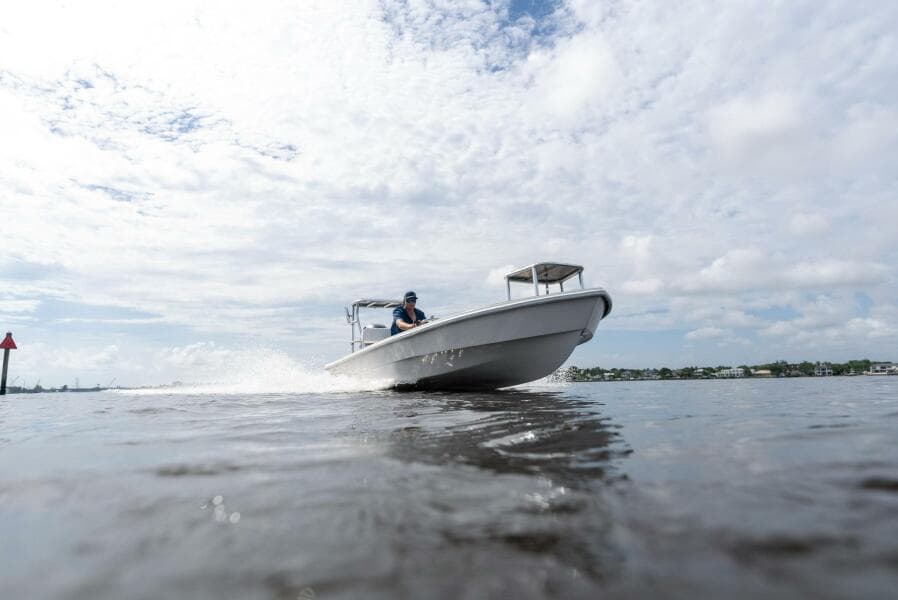 2025 BlueZones Boatworks 16' Flats boat cruising on open water under a cloudy sky.