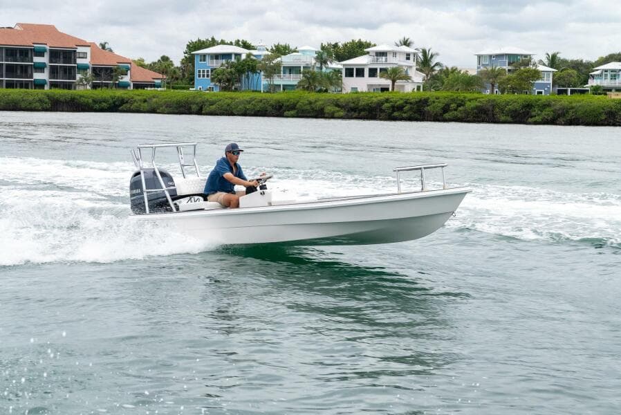 2025 BlueZones Boatworks 16' Flats cruising on water near waterfront homes.