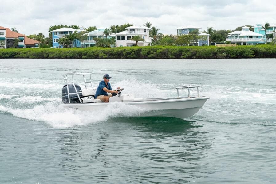 2025 BlueZones Boatworks 16' Flats cruising on water near waterfront homes.