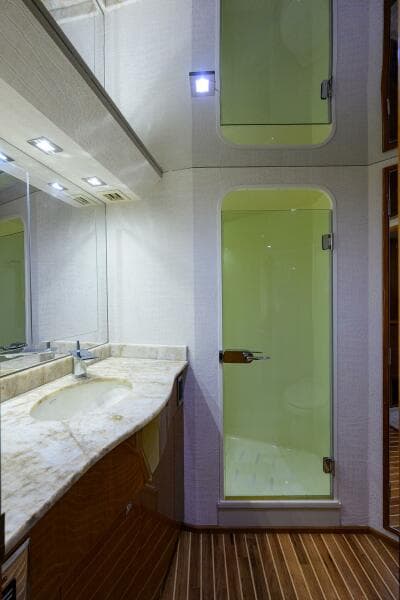 2004 Viking 65 Enclosed Bridge yacht bathroom with marble countertop and glass shower doors.