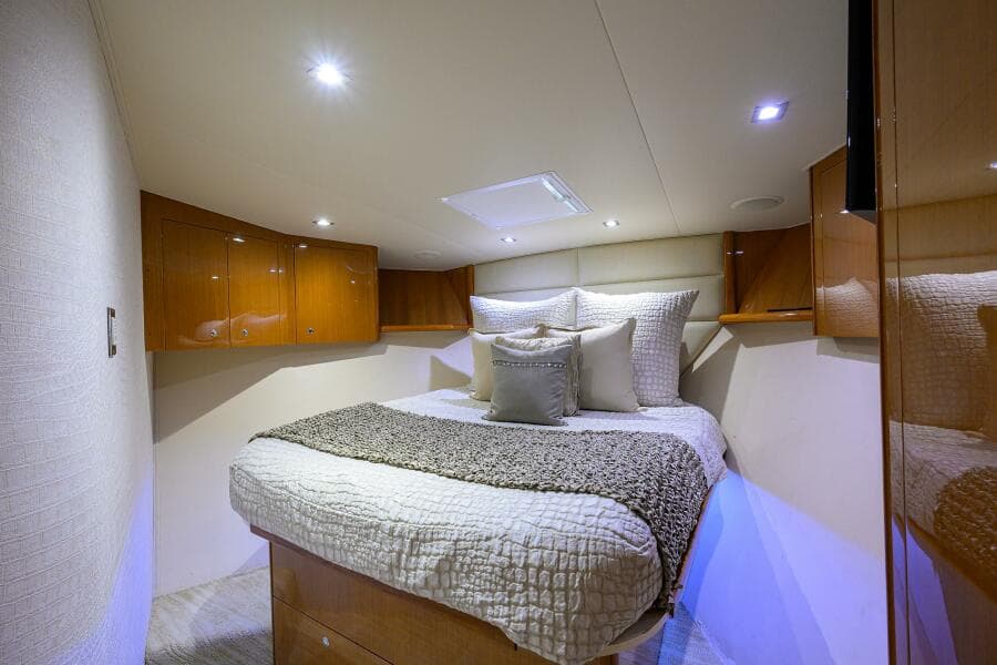 Luxurious bedroom interior of 2004 Viking 65 Enclosed Bridge yacht with cozy bed and wooden cabinets.