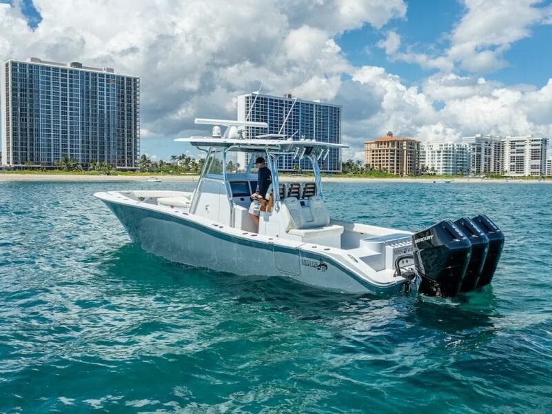 2025 Billfish 39 Center Console boat with tower on clear blue water, city skyline backdrop.