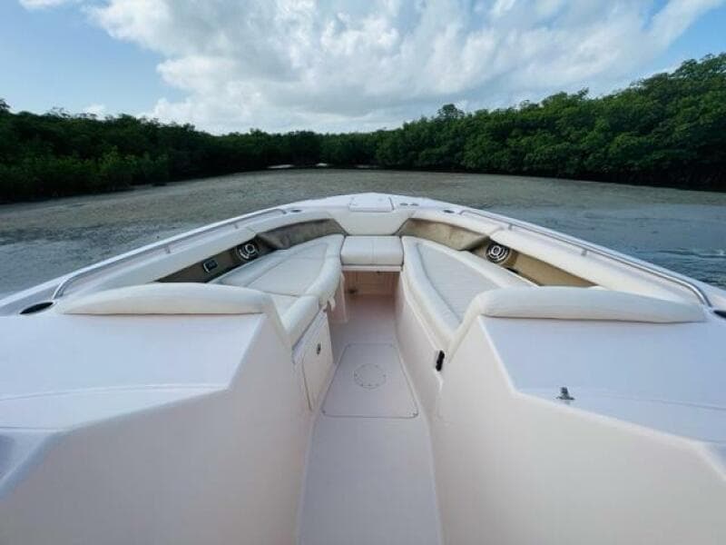 2014 Grady-White Freedom 335 boat with spacious seating, docked near lush greenery.