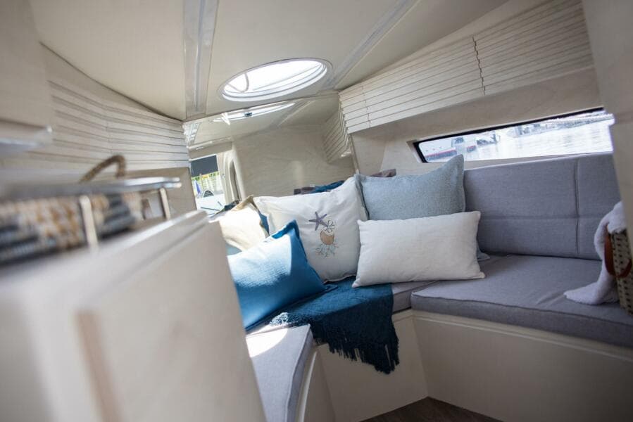 Cozy interior of 2023 Real 35 Special Deck (SD) boat with cushions and natural light.