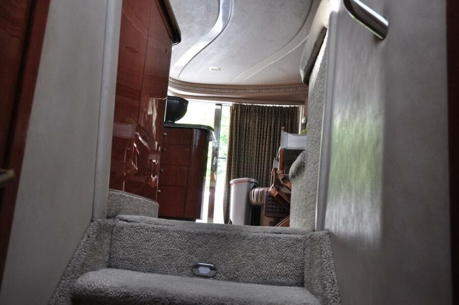 Interior stairs of 1998 Sea Ray 480 Sedan Bridge yacht with carpet and wooden cabinets.