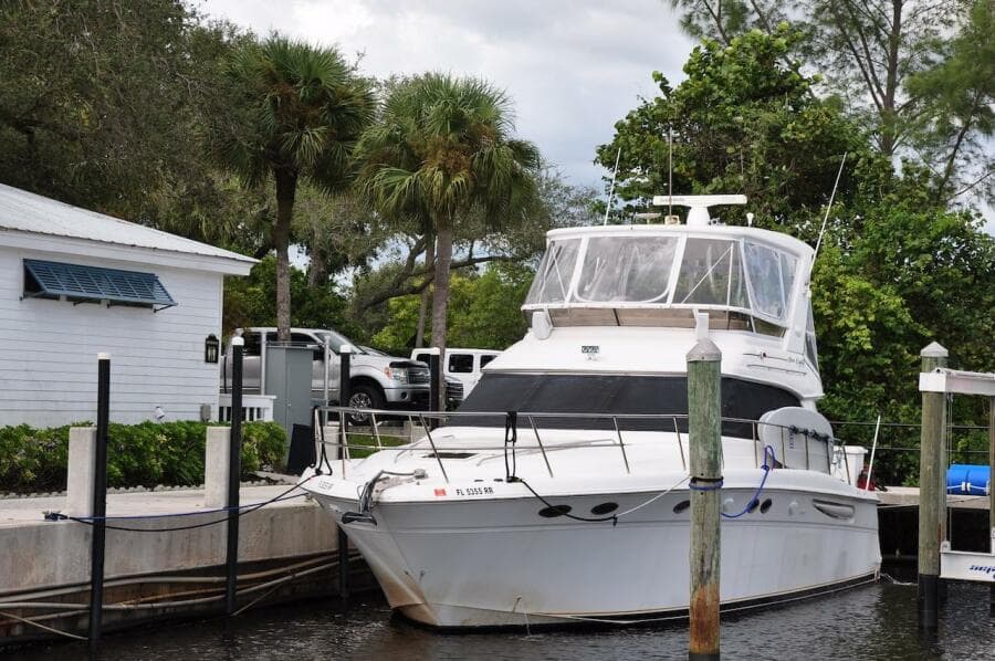 1998 Sea Ray 480 Sedan Bridge docked at a marina with lush greenery.