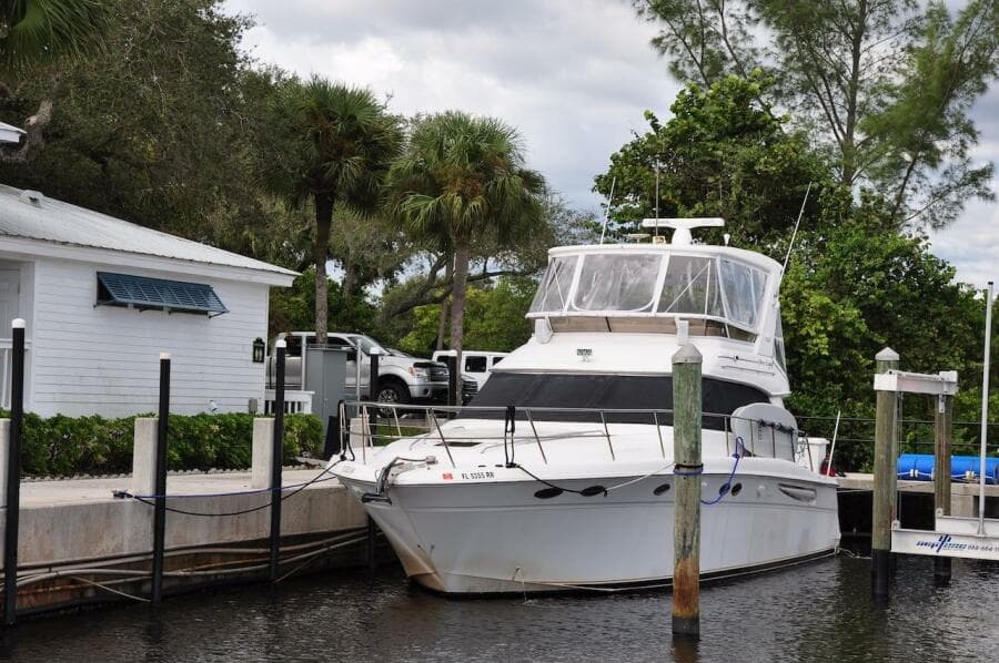 1998 Sea Ray 480 Sedan Bridge yacht docked near a white house.