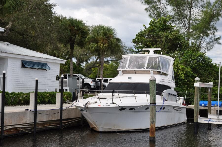 1998 Sea Ray 480 Sedan Bridge yacht docked near a white house.