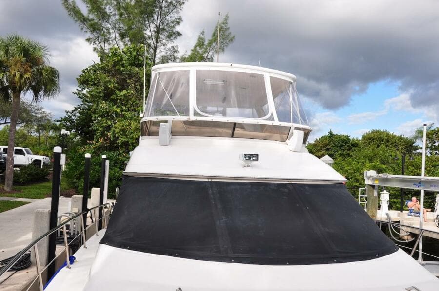 1998 Sea Ray 480 Sedan Bridge yacht docked, front view with clear skies and lush greenery.