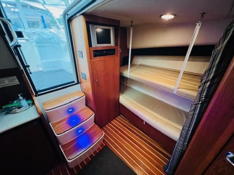 Interior of 2003 Tiara Yachts 3800 Open with bunk beds and illuminated steps.