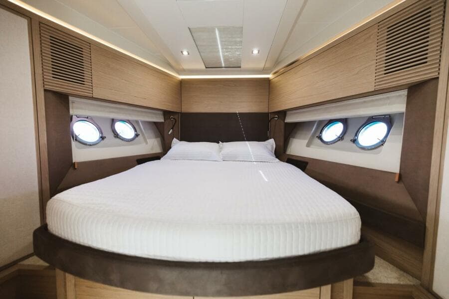 Luxurious bedroom interior of 2015 Beneteau Monte Carlo 5 yacht with round windows.