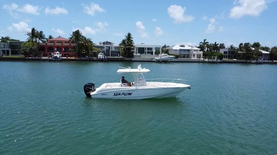 2008 Boston Whaler 320 Outrage boat named Sea Plow on calm water near waterfront homes.