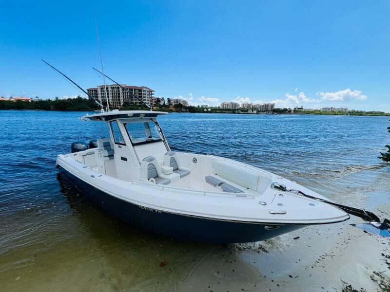 2012 Everglades 295 Center Console boat on sandy shore, blue water background.