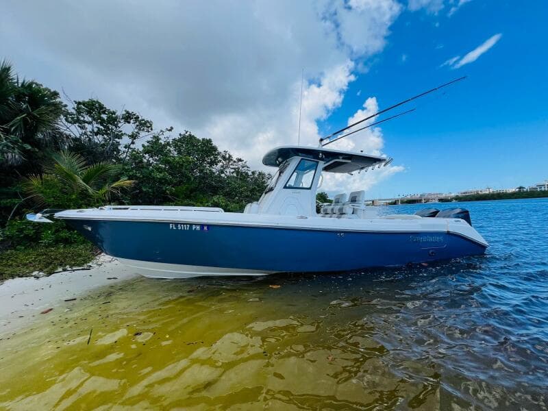 2012 Everglades 295 Center Console boat on a sandy shore, under a partly cloudy sky.
