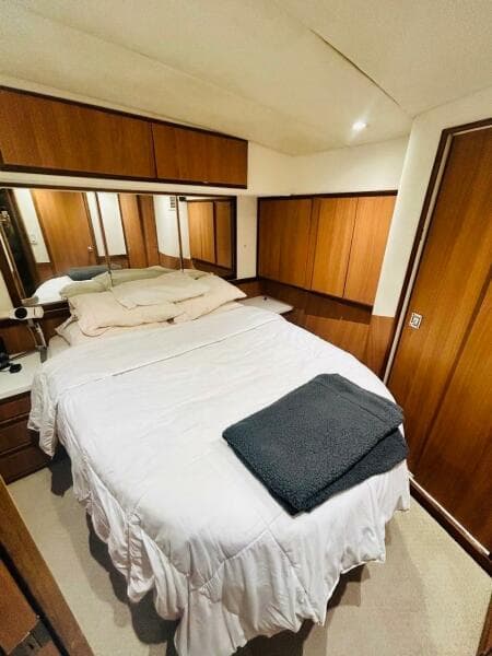 Cozy bedroom in 1988 Bertram 54' yacht with wood paneling and white bedding.
