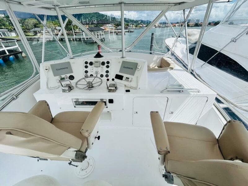 1988 Bertram 54' yacht helm with dual Garmin displays and beige captain chairs.