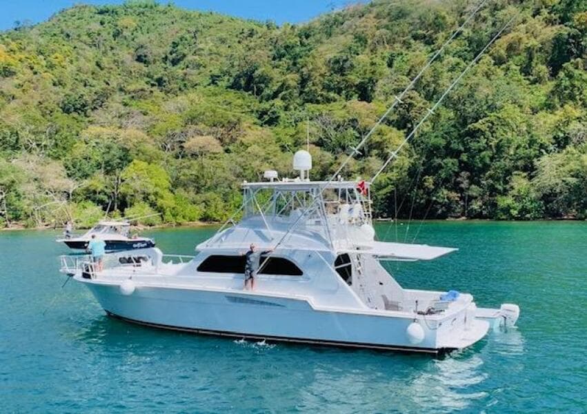 1988 Bertram 54' yacht on serene water, surrounded by lush green hills.