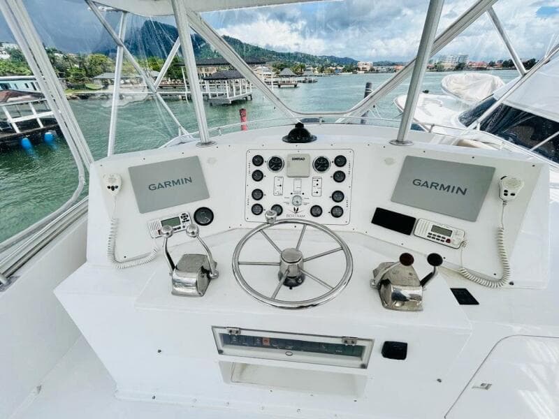 1988 Bertram 54' yacht helm with Garmin navigation, dual controls, and scenic marina view.