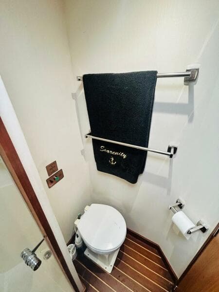 1988 Bertram 54' yacht bathroom with towel, toilet, and wooden floor.