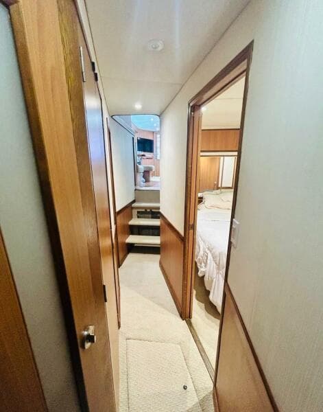 1988 Bertram 54' yacht interior hallway with wood paneling and bedroom view.