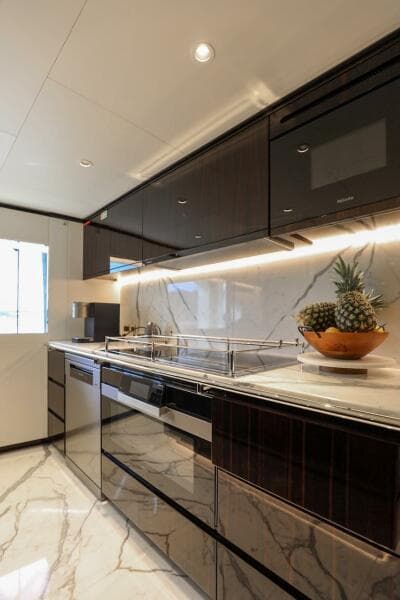 Luxurious kitchen in 2025 Majesty 120 yacht with sleek cabinets and marble flooring.