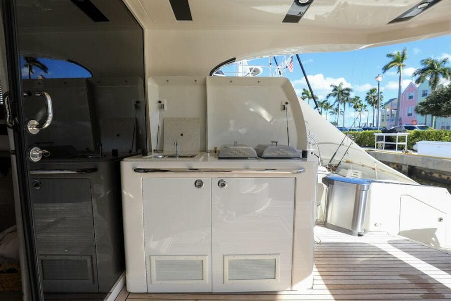 Outdoor kitchenette on 2016 Marquis 660 Sport Yacht with palm trees in background.