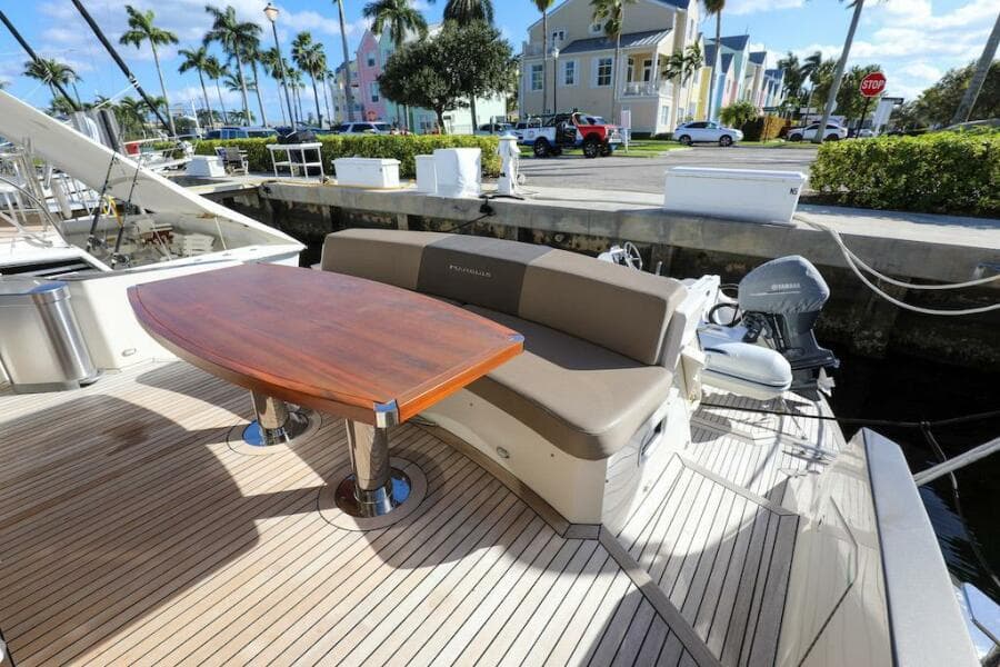 2016 Marquis 660 Sport Yacht deck with seating and table, docked near palm trees.