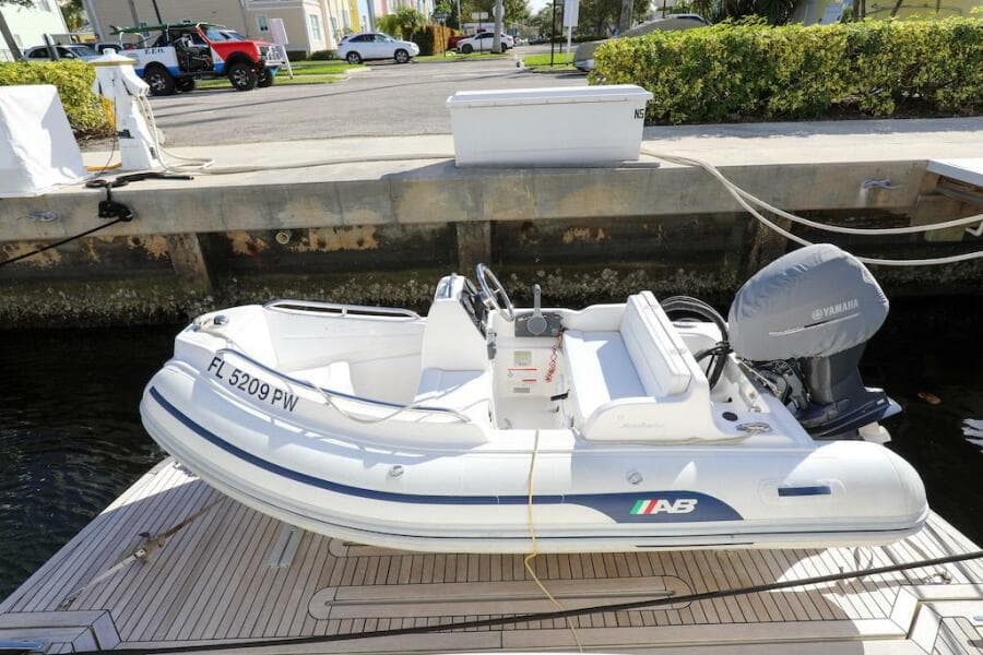 White inflatable boat docked, featuring a Yamaha motor, near a 2016 Marquis 660 Sport Yacht.