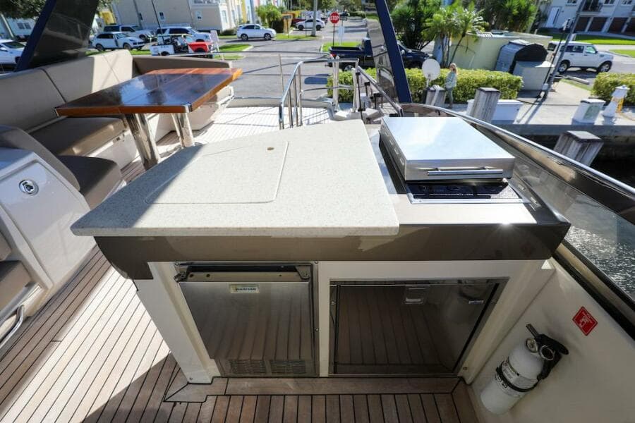 Outdoor kitchen on 2016 Marquis 660 Sport Yacht with grill and seating area.