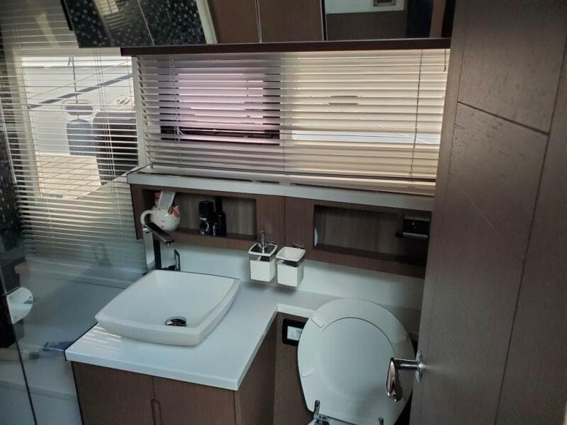 Modern bathroom interior of 2020 Galeon 500 Fly yacht with sink, toilet, and window blinds.