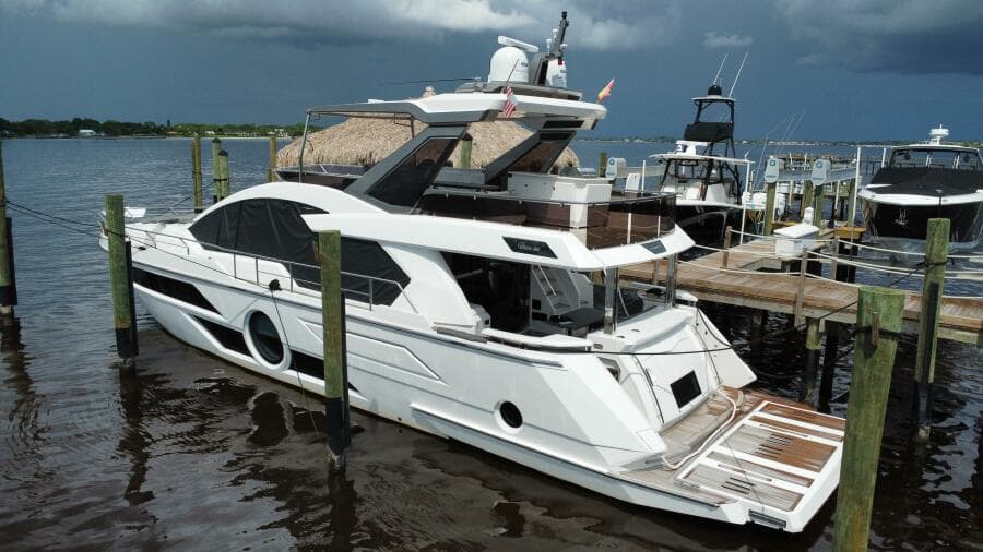 Luxury 2024 Aicon 66 Vivere yacht docked at marina under cloudy sky.