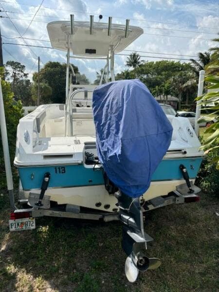 2016 Release 208 RX boat with covered motor, parked on grass.