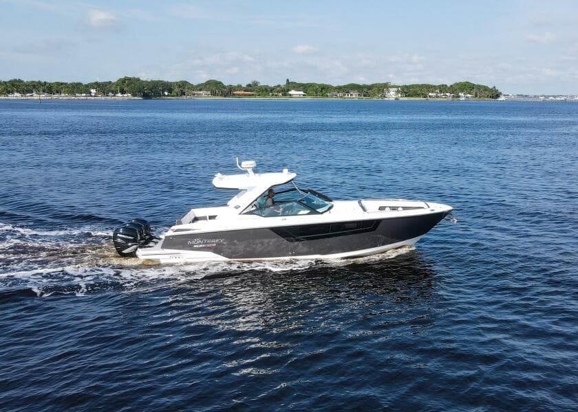2023 Monterey 385 Super Sport cruising on a calm lake under a clear sky.
