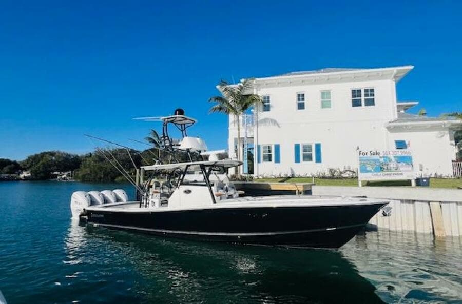2024 Regulator 41 boat docked by waterfront house under clear blue sky.