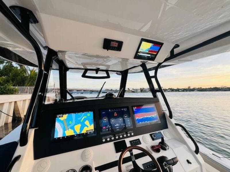 2024 Regulator 41 boat cockpit with advanced navigation displays and steering wheel, docked by the water.