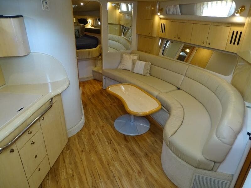 Interior of 2001 Sea Ray 410 Sundancer yacht with curved seating and wooden flooring.