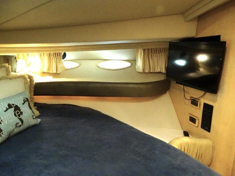 Interior cabin of 2001 Sea Ray 410 Sundancer with bed, TV, and portholes.