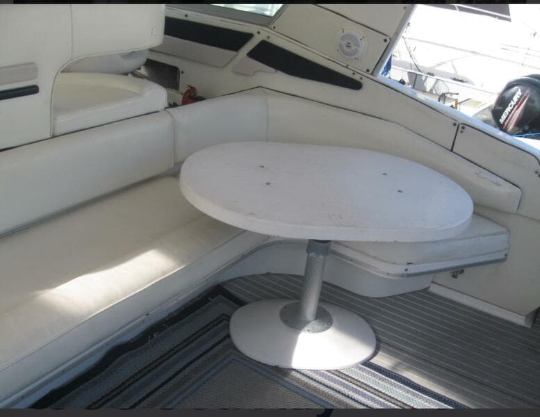 Interior seating area of 1993 Sea Ray 440 Sundancer with white table and cushioned seats.