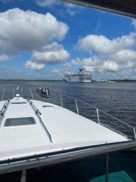 1993 Sea Ray 440 Sundancer on water with cruise ship in background under cloudy sky.