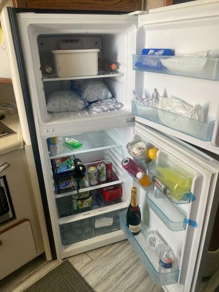 Open refrigerator in a 1993 Sea Ray 440 Sundancer, stocked with drinks and food items.