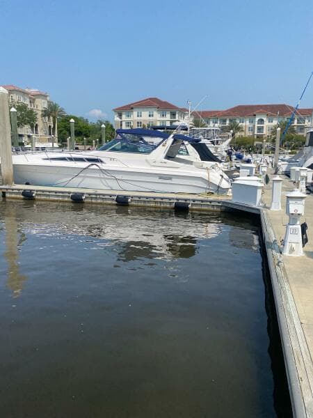 1993 Sea Ray 440 Sundancer docked at a marina with waterfront buildings in the background.