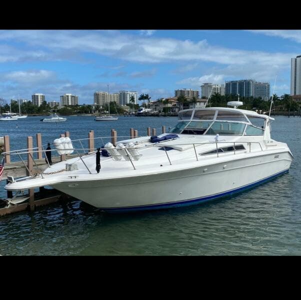 1993 Sea Ray 440 Sundancer yacht docked in a marina with city skyline.